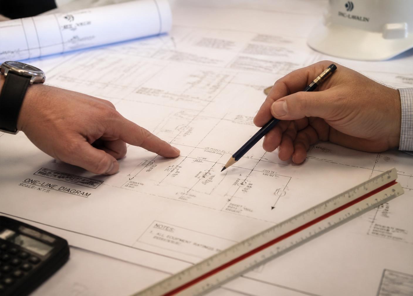 Engineers reviewing an electrical one-line diagram with a scale ruler